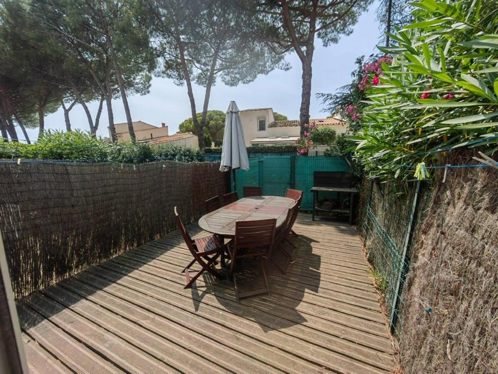 une terrasse en bois avec une table, des chaises et un parasol dans l'établissement Charmant T2 mezzanine climatisé avec piscine, proche plage et loisirs, pour 5 pers. - FR-1-607-77, au Cap d'Agde