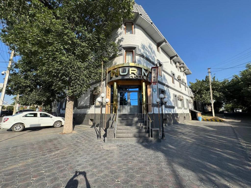 a building with a sign on the front of it at Nur M Hotel in Yakkasaray