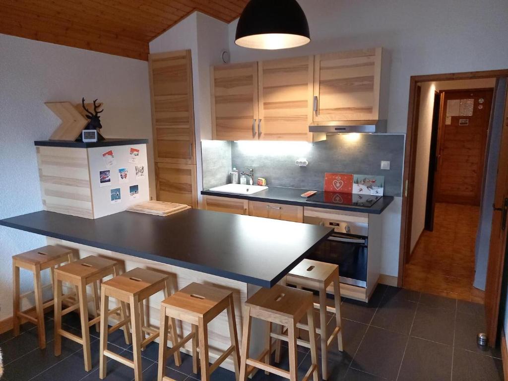 une cuisine avec un comptoir noir et quelques tabourets en bois dans l'établissement Chalet chaleureux à Châtel - Idéal 6 pers, 3 pièces, proche télésiège, WIFI, balcon sud, garage - FR-1-676-21, à Châtel