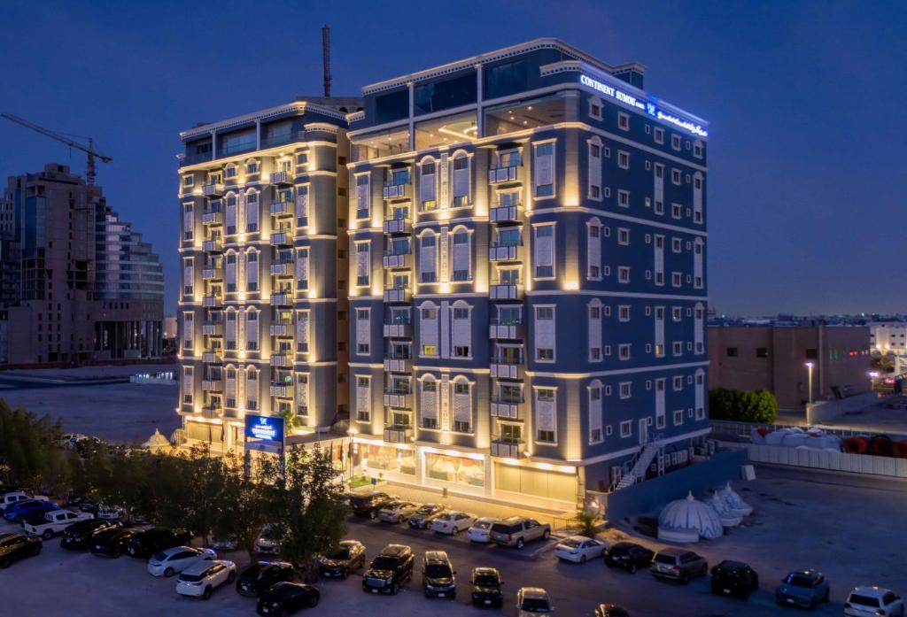a tall building with cars parked in a parking lot at Sumou Hotel Al Khobar in Al Khobar