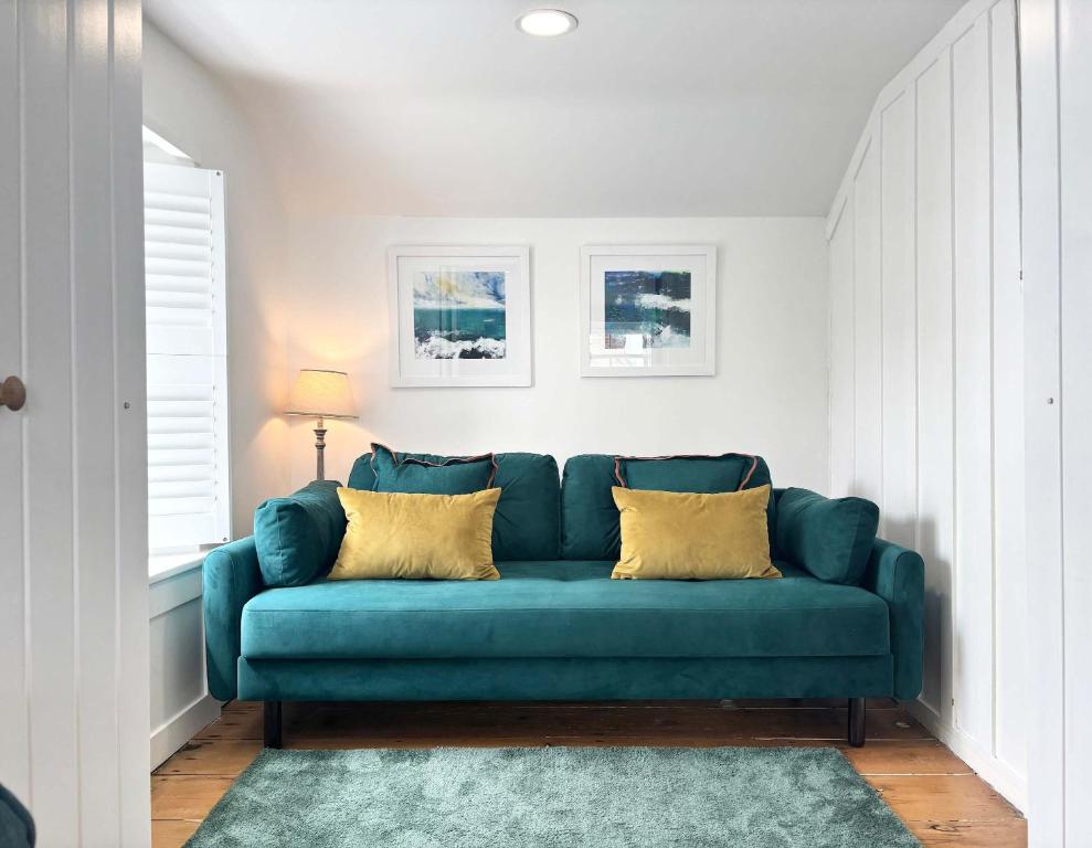 a blue couch in a living room with a rug at Quaint Cosy Cottage Mousehole in Mousehole