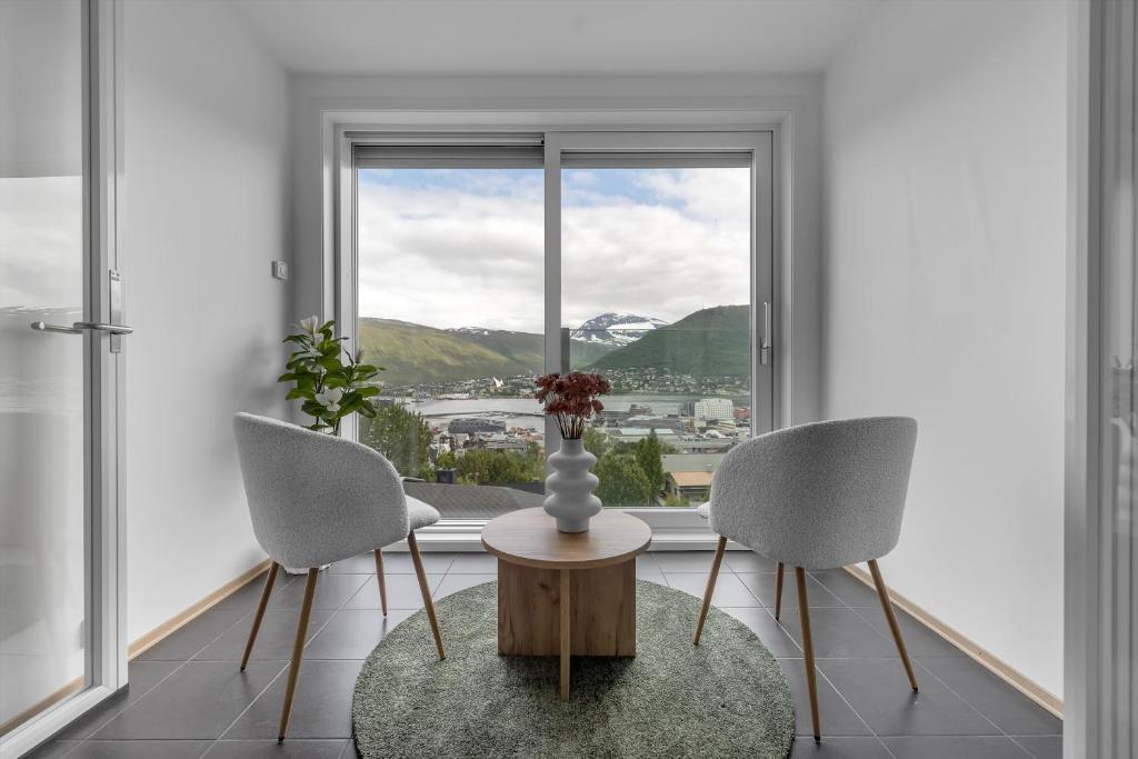ein Zimmer mit zwei Stühlen und einem Tisch und einem Fenster in der Unterkunft Northstay - Tromsø Outlook, Amazing City & Mountain Views in Tromsø