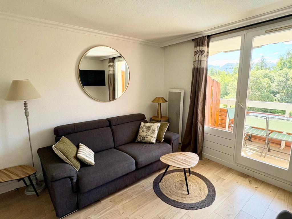un soggiorno con un divano e uno specchio di Pierre et Vacances Les Bergers au Pied des pistes & Piscine -Sauna & Balcon Sud a LʼAlpe-dʼHuez