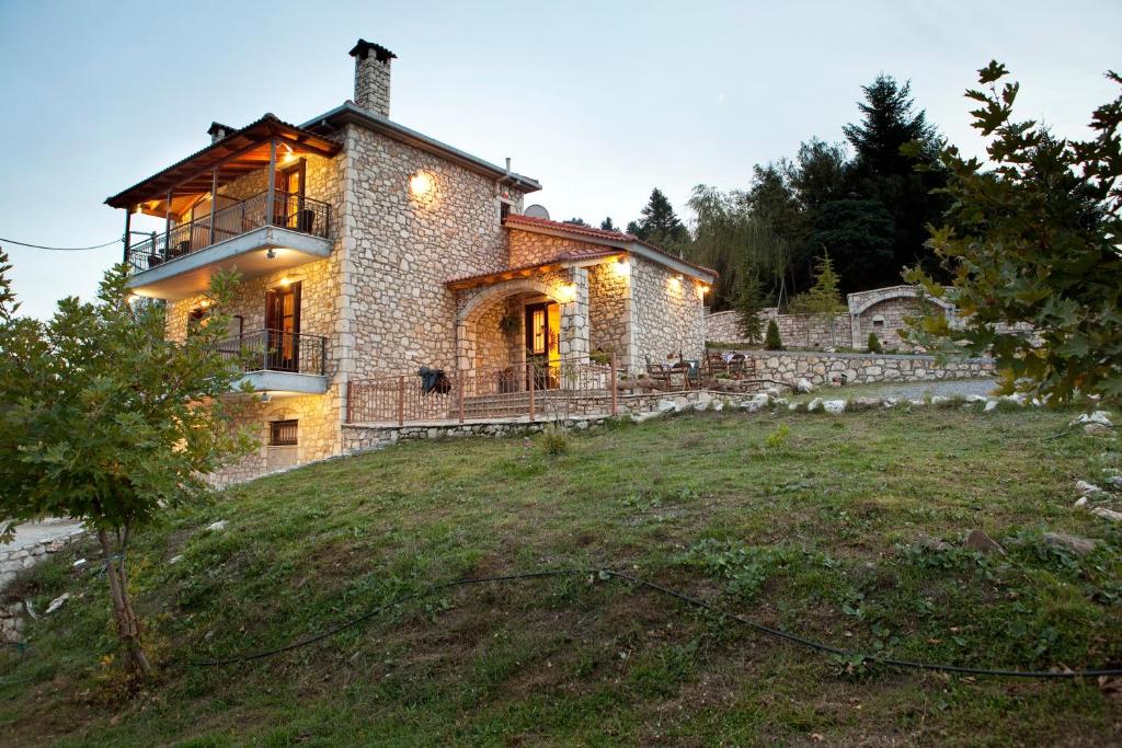 a large stone house on a hill with a yard at Kaloneri Rooms in Kaloneri