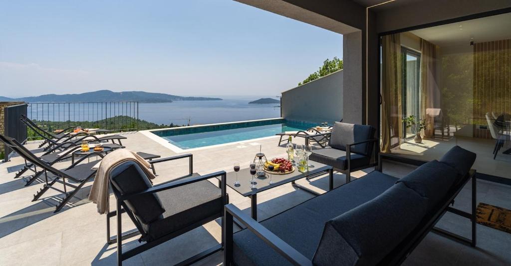 a patio with chairs and a table and a pool at Green Sunrise Villa in Brsečine