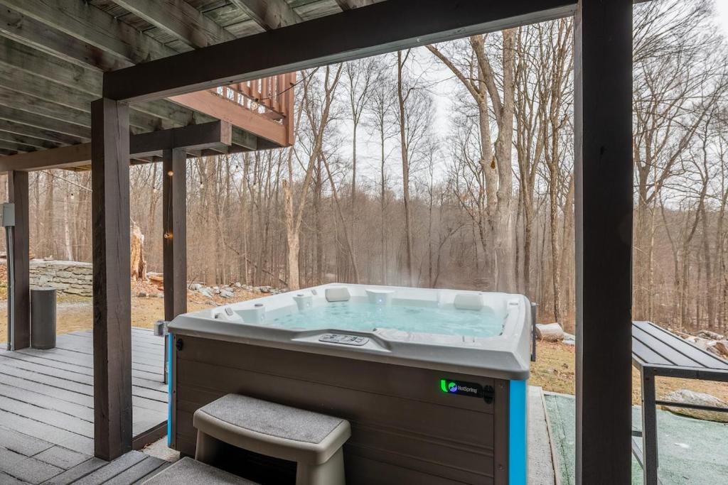 a hot tub on a deck with a view of the woods at 5 min to Lake Chic Cozy Hot Tub in Sparta