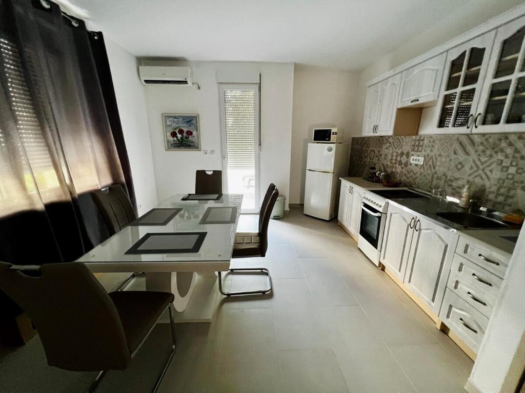 a kitchen with white cabinets and a table and chairs at Center Oasis Retreat in Podgorica