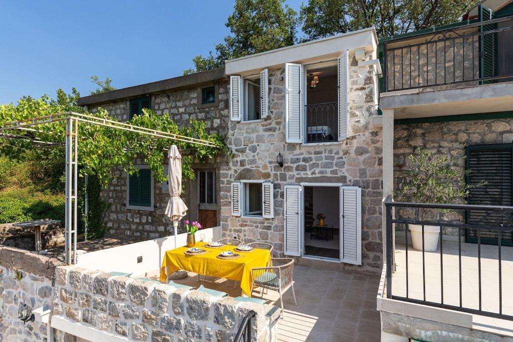 にあるLuxury Villa Pjetraのパティオに黄色いテーブルが置かれた石造りの家