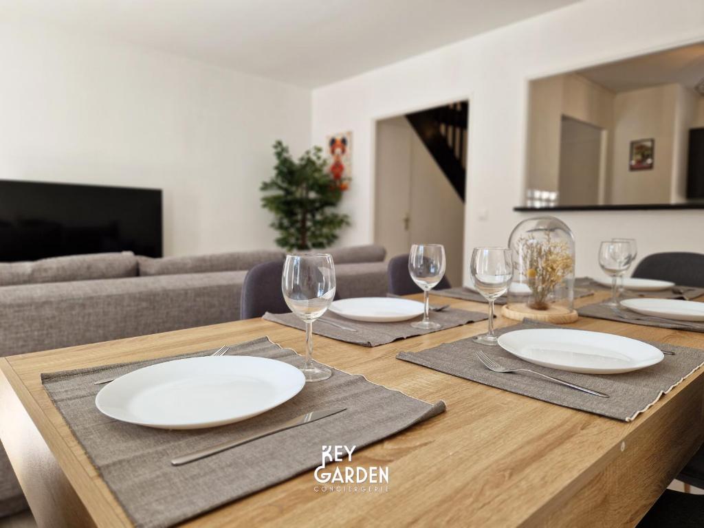 バイー・ロマンヴィリエにあるHouse for 10 people, Disneylandの皿とワイングラスが置かれた木製のテーブル