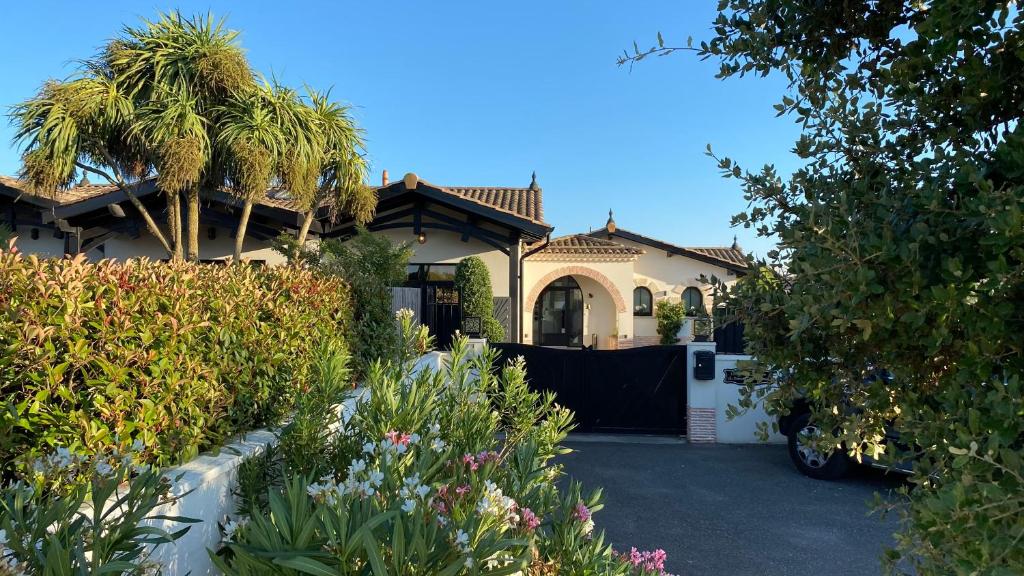 une maison avec des palmiers et une allée dans l'établissement Hôtel particulier - Les lodges du Bassin d'Arcachon- Petit-déjeuner sur demande- Prestations haut de gamme, à Gujan-Mestras