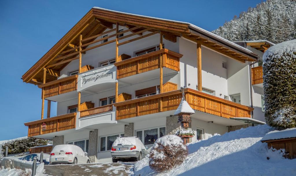a large building with a balcony in the snow at Pension Grohmann in Santa Cristina in Val Gardena