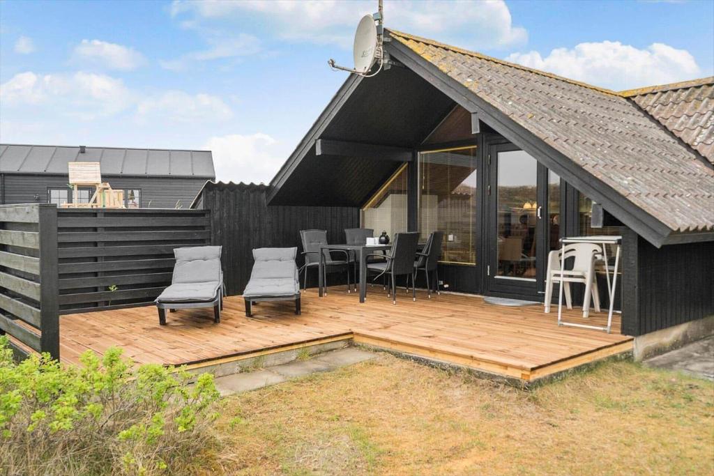 a black house with a wooden deck with chairs at 601-Hvide-Sande-Bjerregardsvej-375 in Bjerregård
