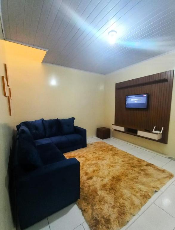 a living room with a blue couch and a flat screen tv at AP Luz do Sol in Campina Grande do Sul