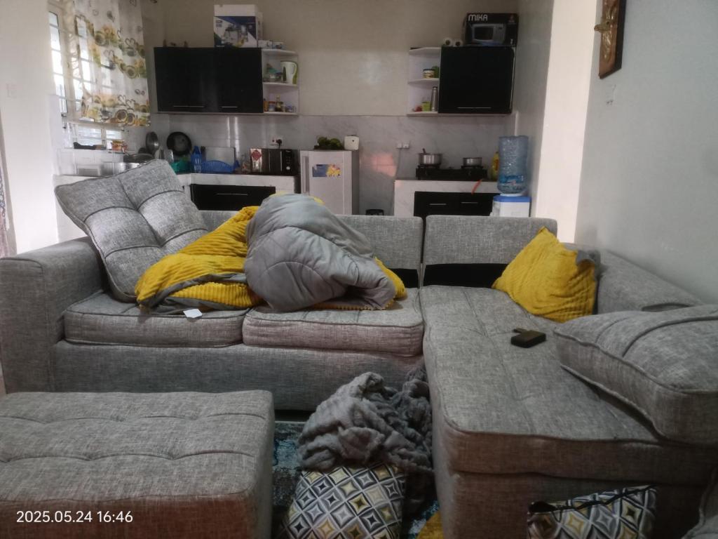 a living room with a gray couch and yellow pillows at kire homes in Nakuru