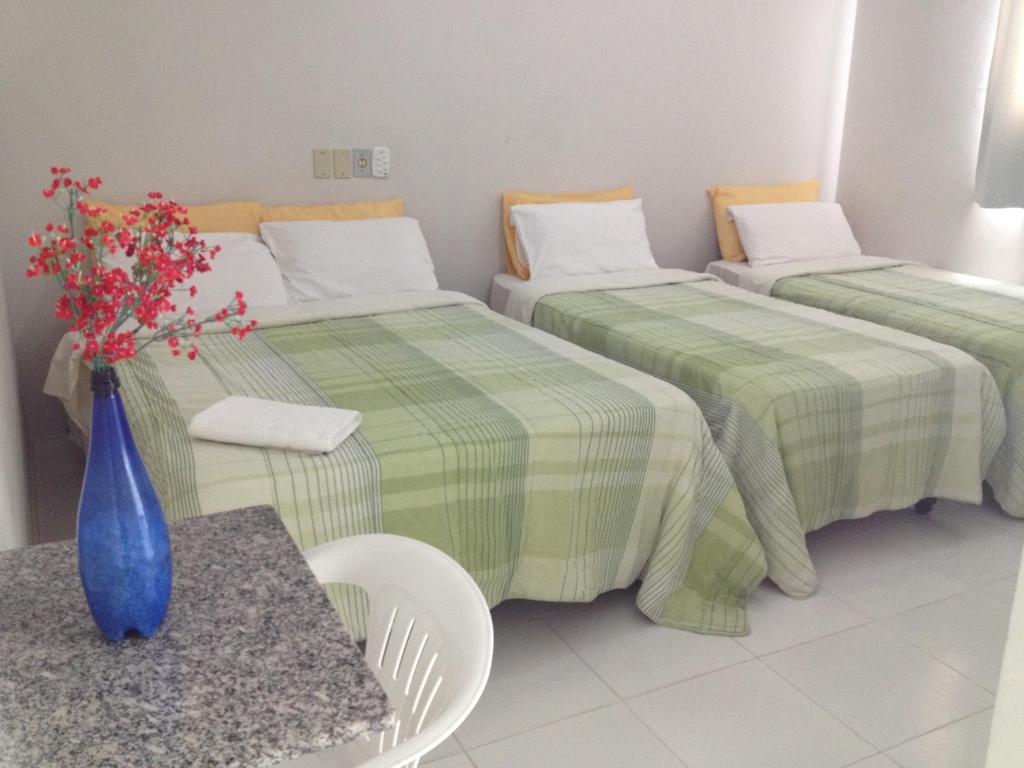 a room with two beds and a vase of flowers on a table at BLUES HOTEL in Guaratinguetá