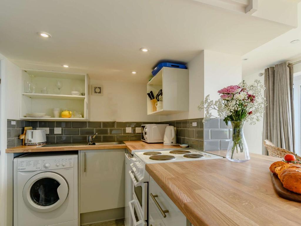 a kitchen with a washing machine and a vase of flowers at 1 Bed in Tresaith 89316 in Penbryn