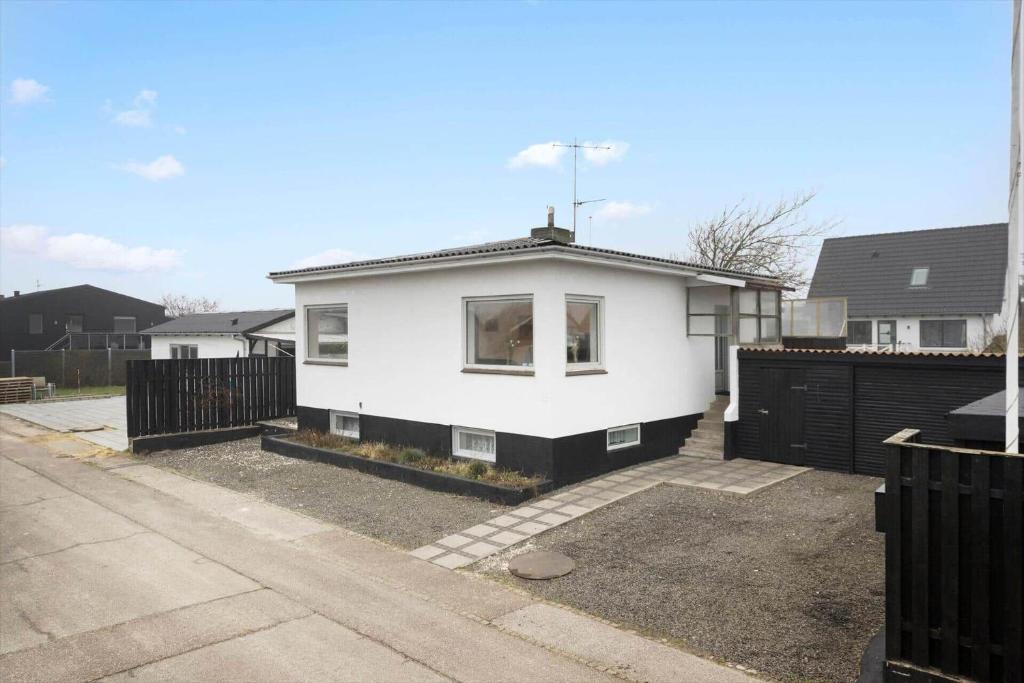 ein weißes Haus mit einem Zaun in einer Einfahrt in der Unterkunft 8817 Hvide Sande - Mågevej 2 in Hvide Sande