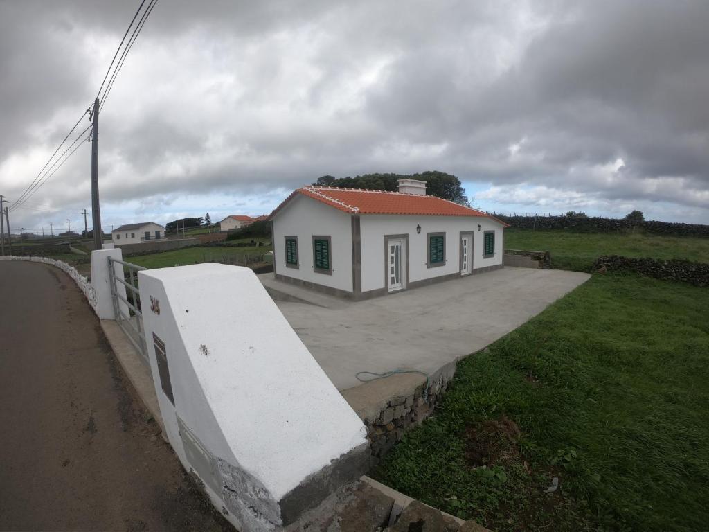 a small white house in a field with a fence at Quinta do José - AL in Praia da Vitória