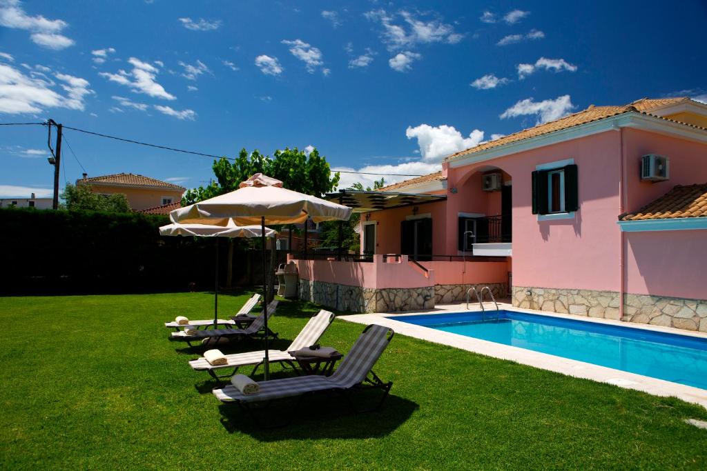 una piscina con sillas y una sombrilla junto a una casa en Anthemis Luxury Villas, en Ligia