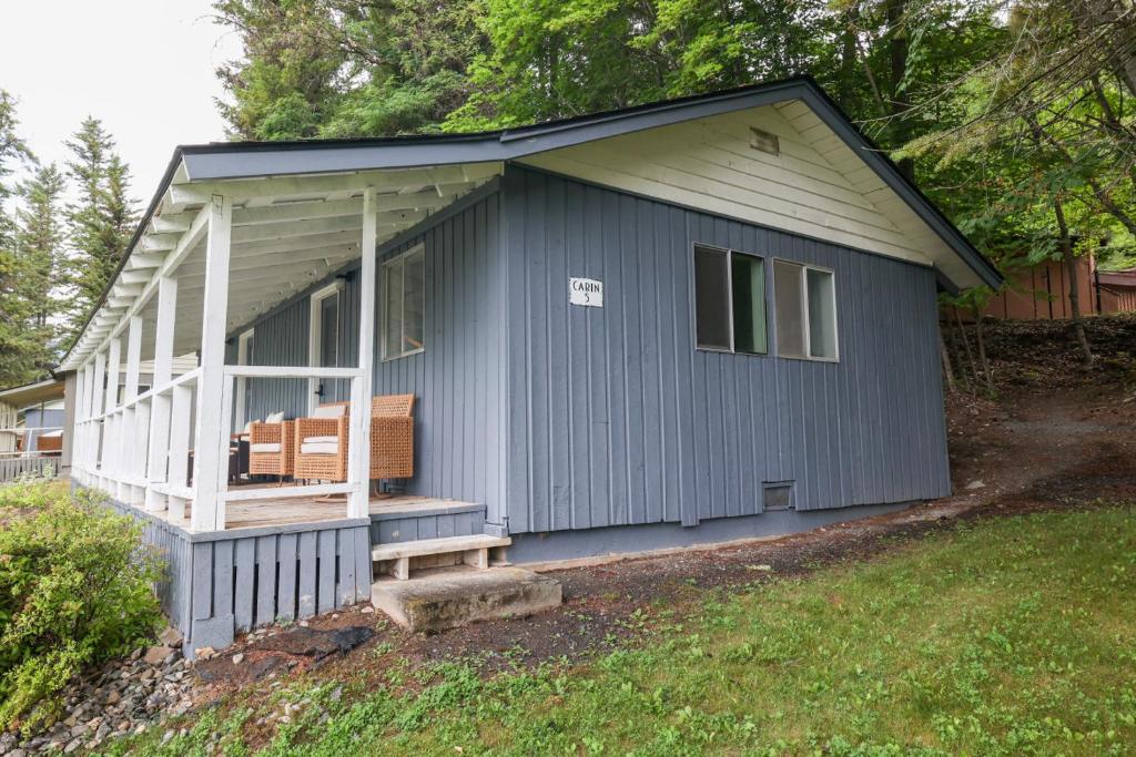 a blue shed with a porch and a bench at Wilderness West Resort Cabin 5 in Colville