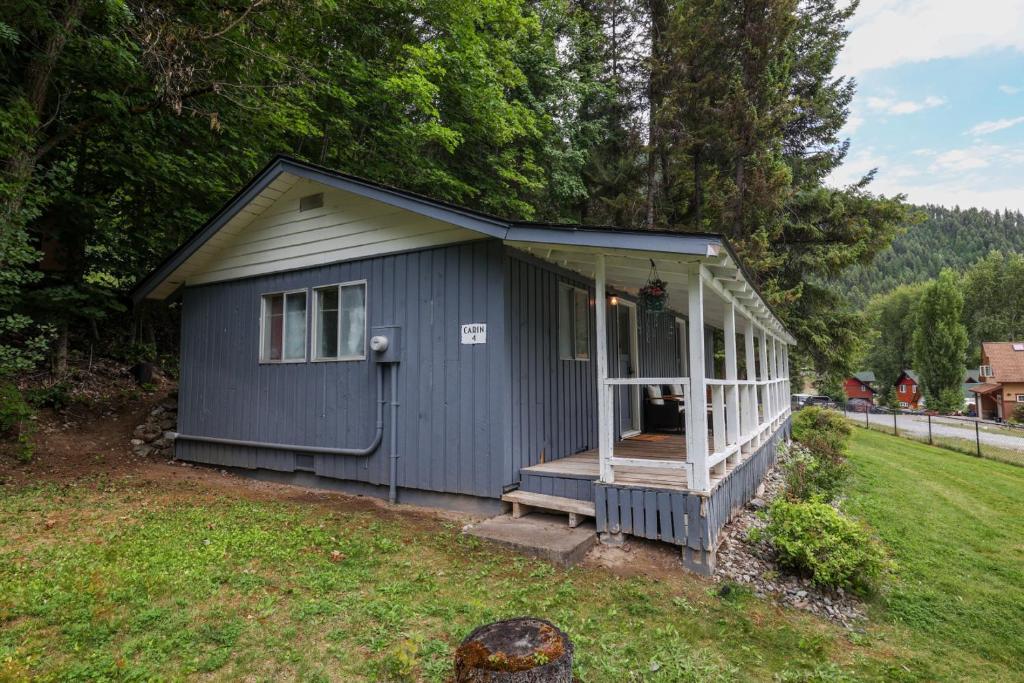 a small blue shed with a porch in a yard at Wilderness West Resort Cabin 4 in Colville