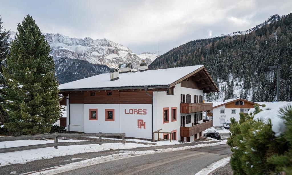 a building in the mountains with snow on the ground at Apartments Lores in Selva di Val Gardena