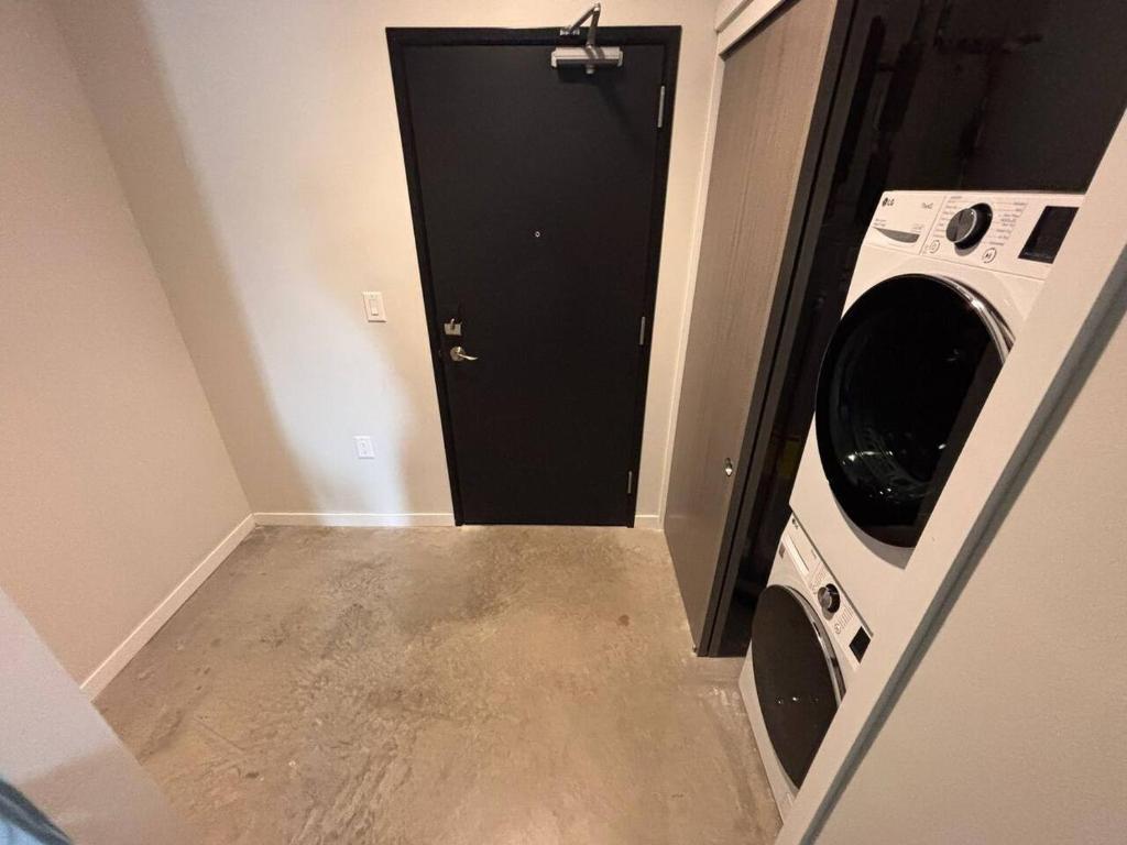 a laundry room with a black door and a washing machine at Charcoal Loft in Des Moines