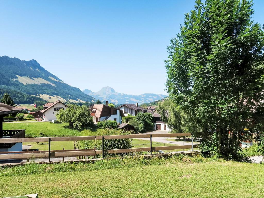 a wooden fence in a field with mountains in the background at Apartment Chalet Clairval by Interhome in Charmey