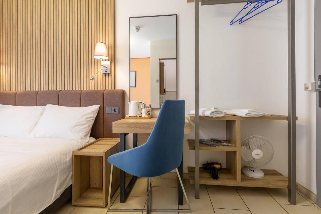 a bedroom with a bed and a blue chair next to a desk at Nani City Hotel Self Check-In in Zurich