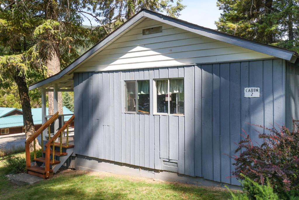 a blue shed with a window and a sign on it at Wilderness West Resort Cabin 2 in Colville