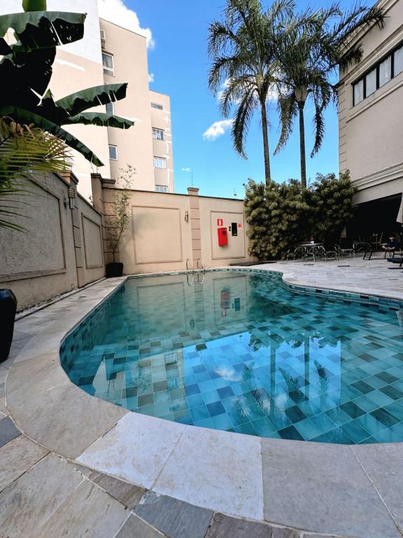 a swimming pool with blue tiles on the floor and a building at Class Hotel Guaxupé in Guaxupé