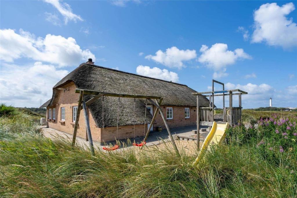 an old brick building with a playground in a field at 362-Hvide-Sande-Fyrmarken-35 in Hvide Sande
