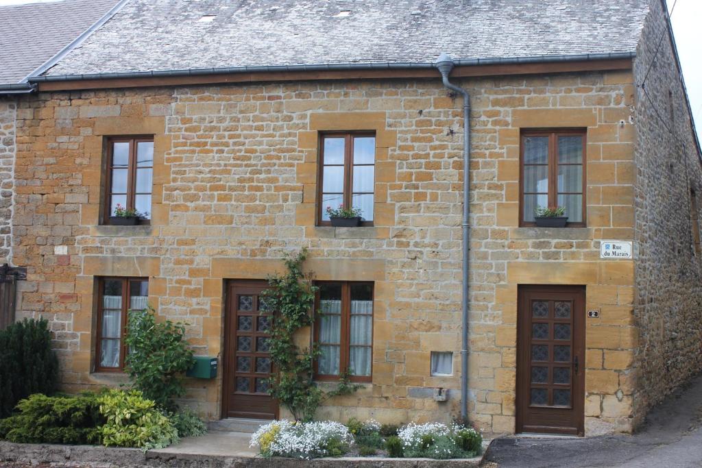 une maison en briques avec des portes et des fenêtres marron dans l'établissement gite de la ruelle des messes, à LʼÉchelle