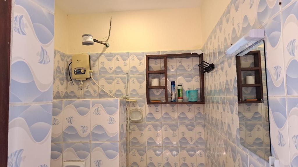 Un baño con ducha con azulejos azules y blancos. en Diani Savanna Sunset Studio Apartment, en Diani Beach