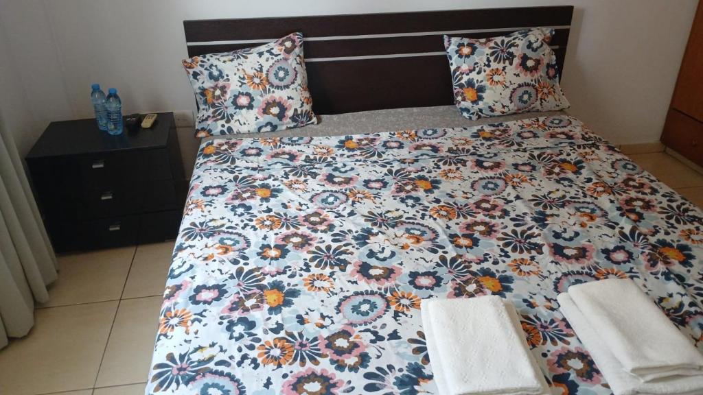 a bed with a floral comforter and two pillows at Unique City room in Larnaka