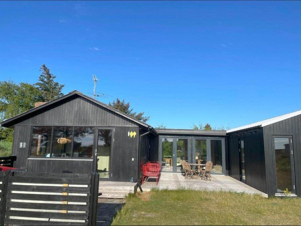 a black house with a deck and a patio at 3398-Hvide-Sande-Anker-Eskildsens-Vej-100 in Hvide Sande
