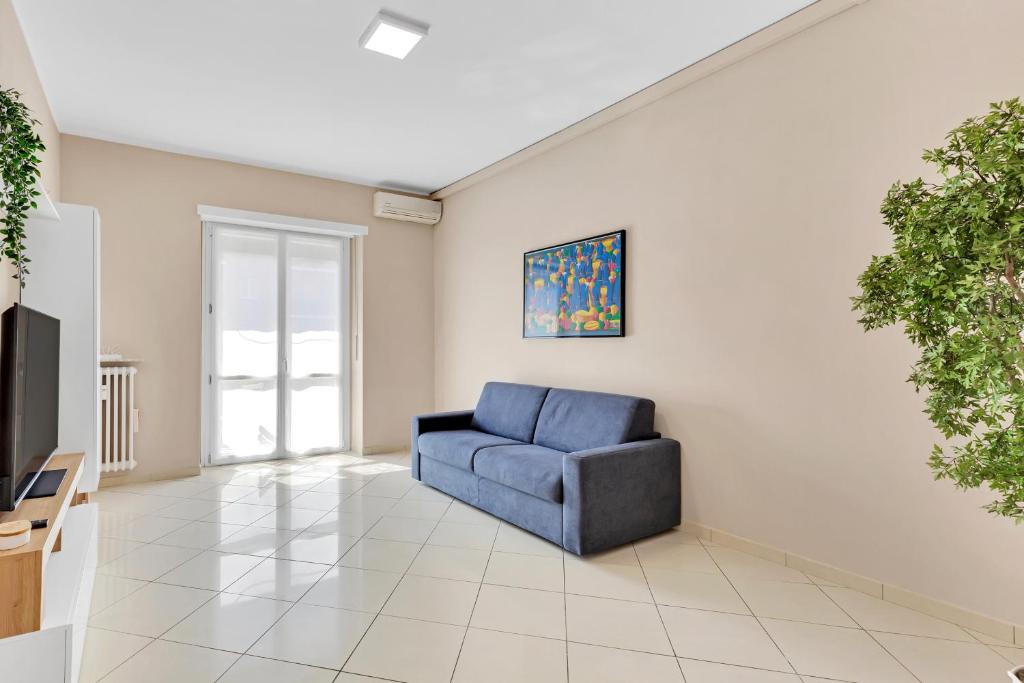 a living room with a blue chair and a television at Casa Torino - Rho Fiera Stay in Rho