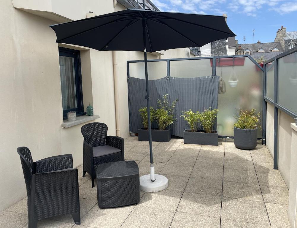 a patio with two chairs and an umbrella at La terrasse de l'Amirauté in Dinan