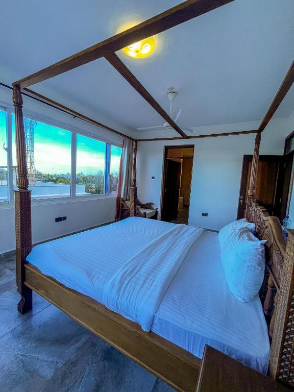 a bedroom with a large bed with a large window at Diani Epic Two Bedroom Apartment in Diani Beach