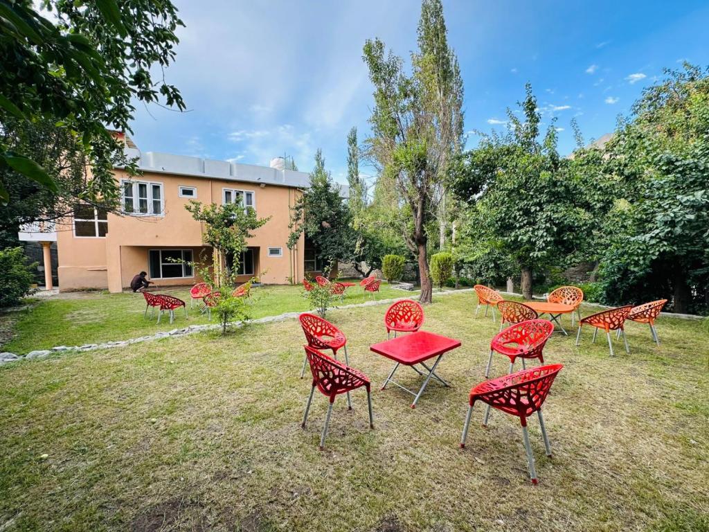 a group of red chairs and tables in a yard at Qasr-e-Ashraf in Skardu