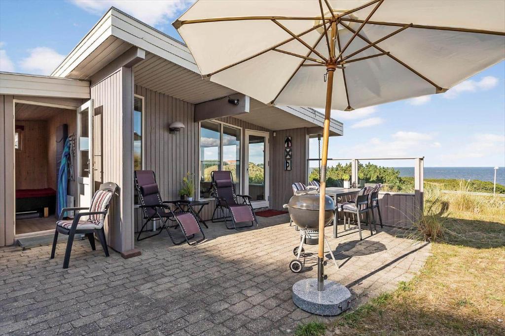 eine Terrasse mit Sonnenschirm und Tisch und Stühlen in der Unterkunft 755 Hvide Sande - Søndergade 106 in Hvide Sande