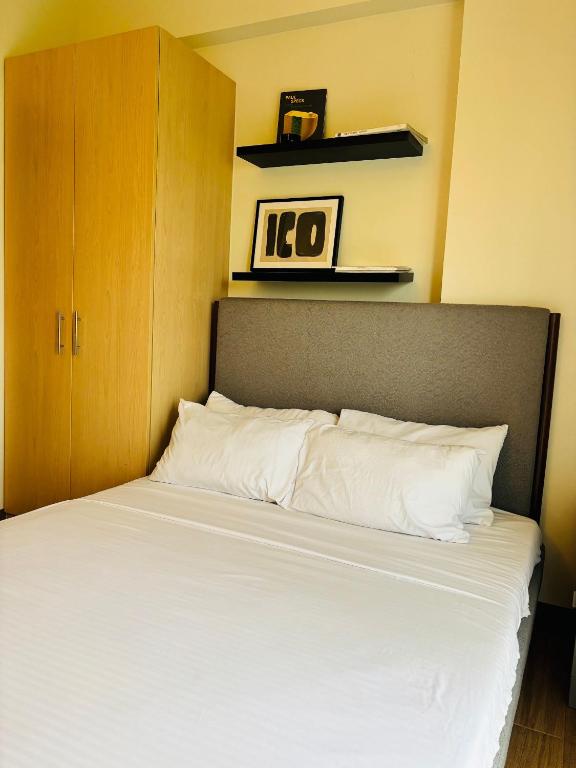 1 cama con sábanas blancas y armario de madera en Nature Lovers Paradise in Iloilo City - Cozy Condo Rental, en Iloilo City