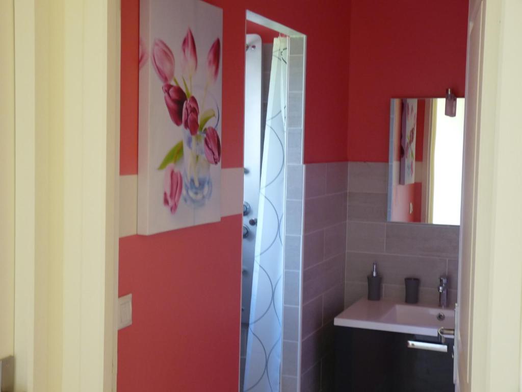 ein Bad mit roten Wänden, einem Waschbecken und einem Spiegel in der Unterkunft Maison Bel Air in Pimbo