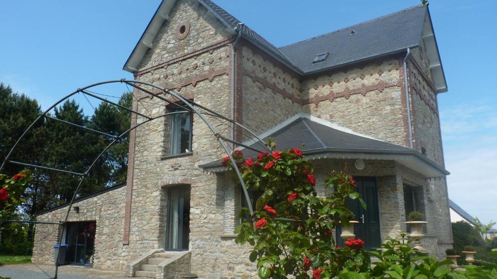 ein Backsteingebäude mit roten Blumen davor in der Unterkunft La maison des musiciens in Digosville