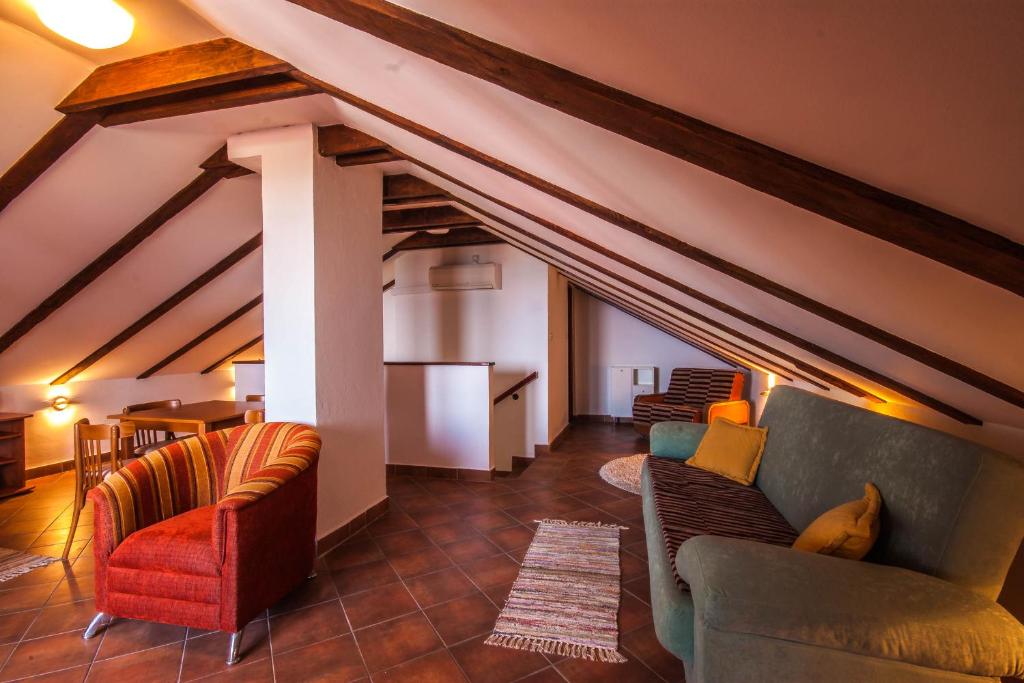 a living room with couches and chairs in an attic at Apartman Joso in Diklo