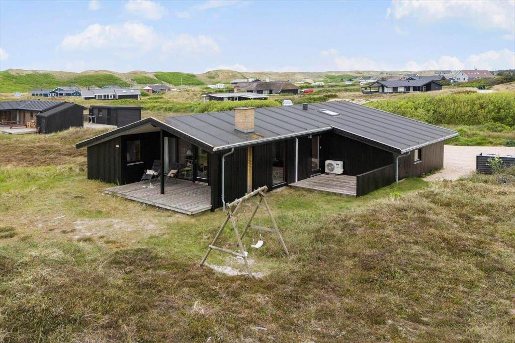 a black house sitting on top of a field at 467-Hvide-Sande-Tingodden-212 in Hvide Sande
