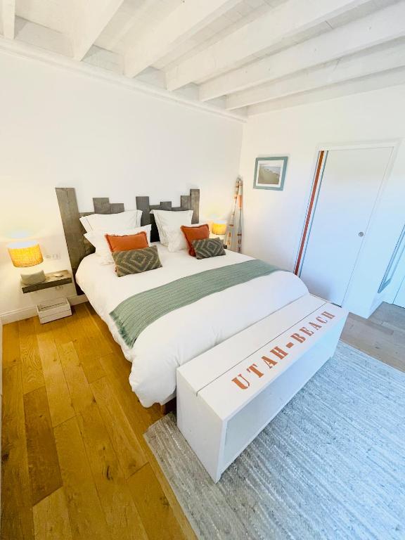 a bedroom with a large white bed in a room at Ferme les Chapelles Utah Beach in Angoville-au-Plain