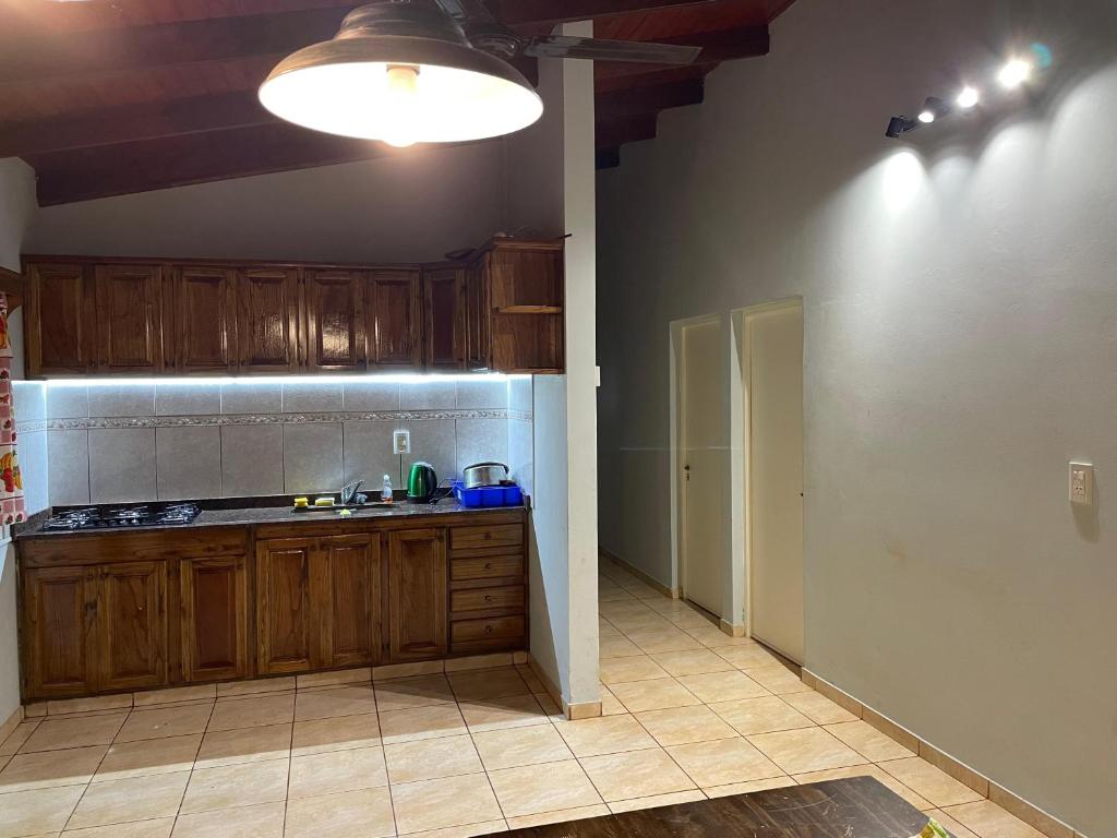 Una cocina con gabinetes de madera y encimera. en Casa Atardecer, en Eldorado