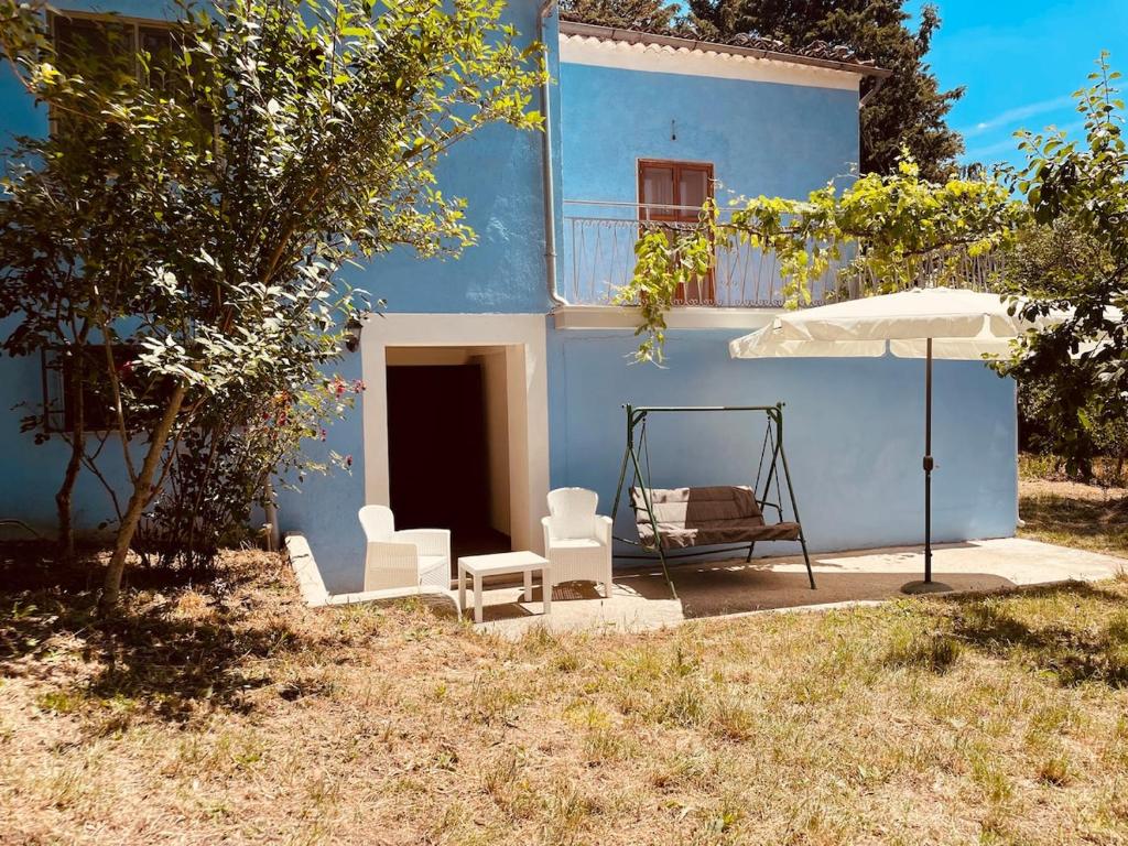 a blue house with two chairs and an umbrella at Holiday Home Tenuta Santella in Gildone