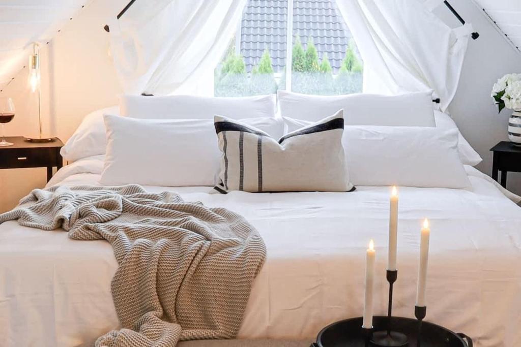 a white bed with two candles on top of it at Fully Equipped Home Close to Malmö &amp; Copenhagen in Vellinge
